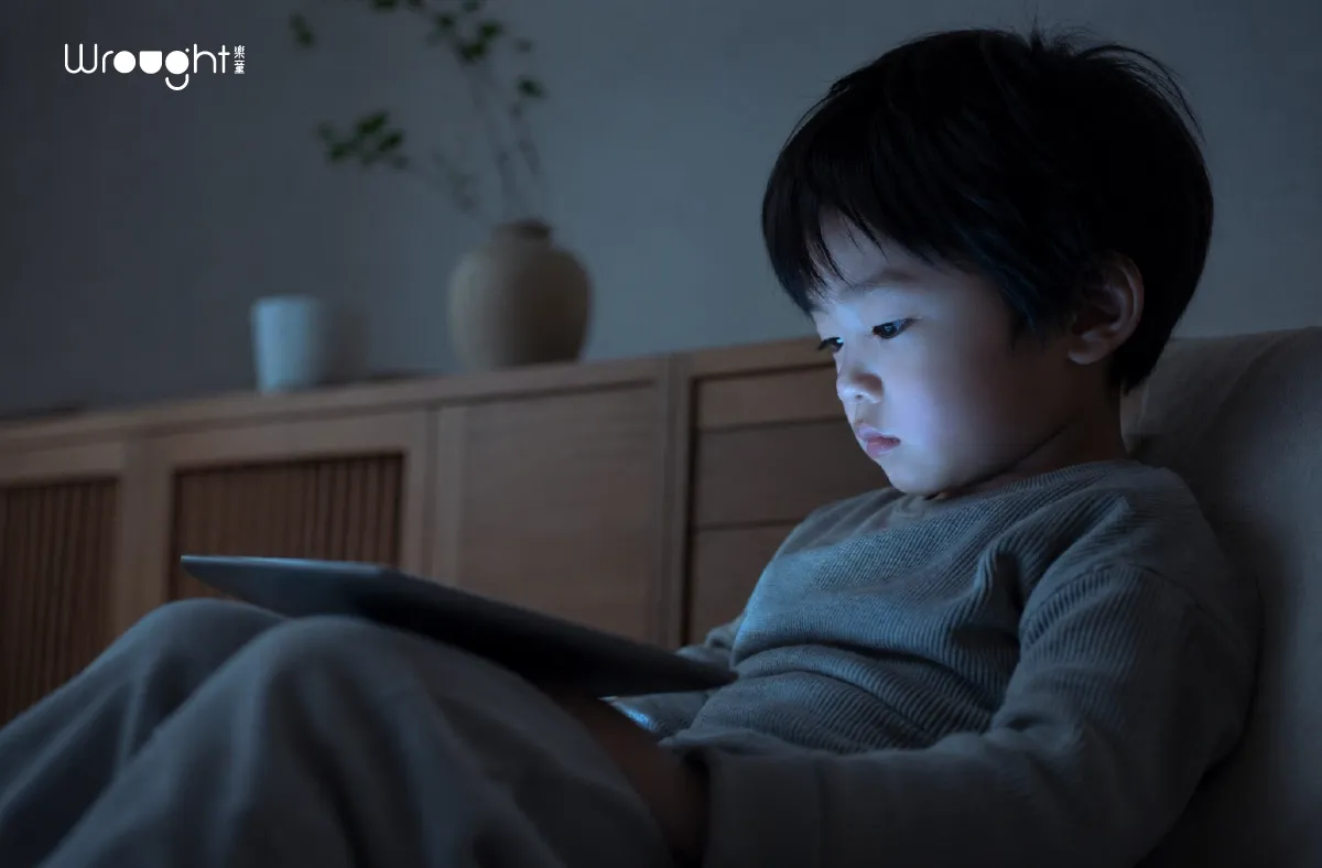 孩子3C使用時間-孩子在昏暗環境中獨自使用平板,臉部被螢幕藍光照亮,呈現過度依賴3C的警示情境